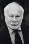A man with white hair and beard wearing a suit.