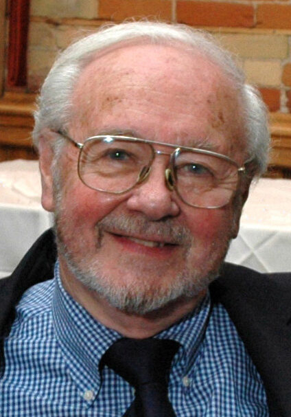 A man with glasses and a beard wearing a suit.