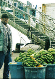 A man standing next to buckets of bananas.