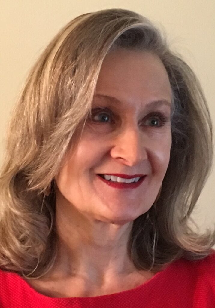 A woman with long hair wearing red is smiling.