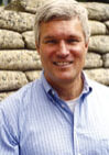 A man in a blue shirt standing next to a wall.