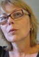A woman with glasses is looking at the camera.