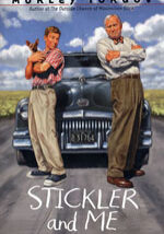 Two men standing in front of a car on the road.